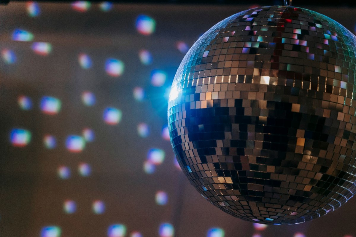Event floor with a mirror ball, coloured wash lighting and adult guests dancing